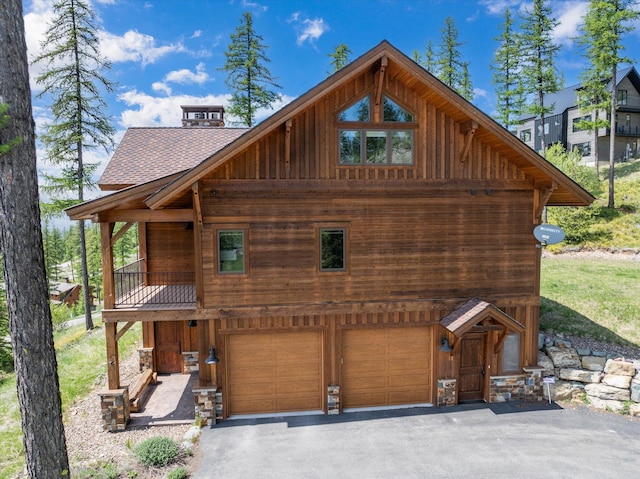 476 Elk Highlands Dr, Whitefish, MT 59937 - view of front facade with a shingled roof, asphalt driveway, an attached garage, and board and batten siding
