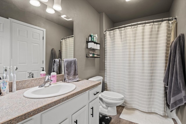 full bathroom with toilet, visible vents, wood finished floors, and vanity