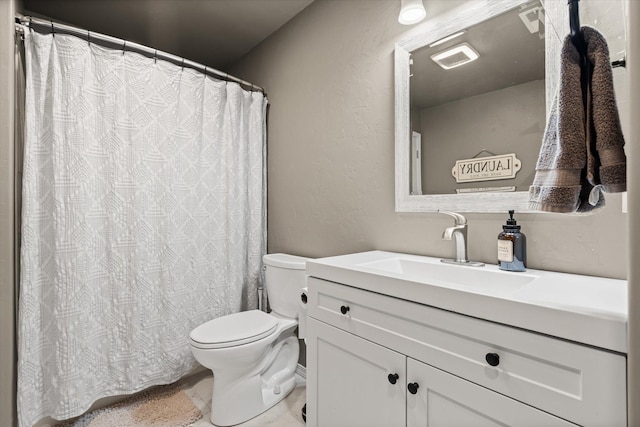 full bath with a textured wall, vanity, and toilet