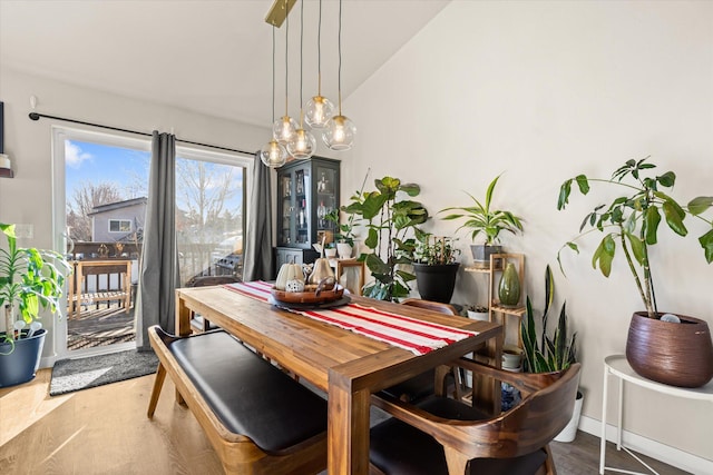 dining area featuring vaulted ceiling, wood finished floors, and baseboards