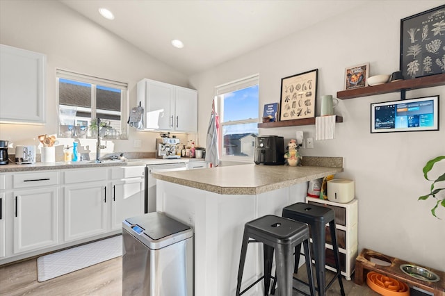 kitchen with white cabinets, a breakfast bar area, a peninsula, vaulted ceiling, and open shelves