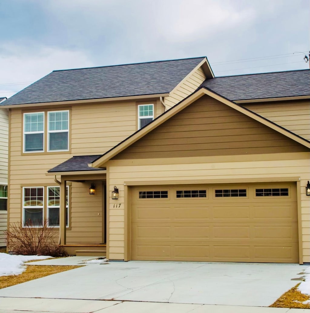 view of front of home with an attached garage, concrete driveway, and roof with shingles