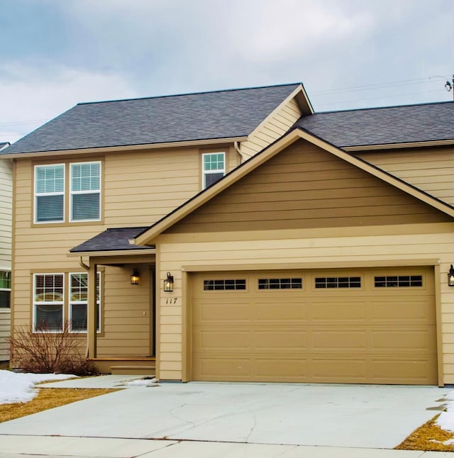 view of front of home with an attached garage, concrete driveway, and roof with shingles