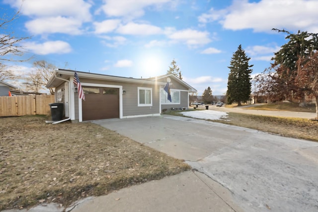 view of front facade featuring a garage, concrete driveway, and fence