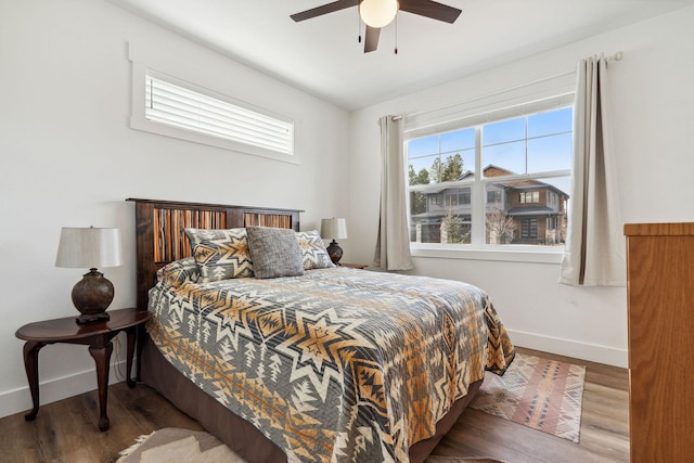 bedroom with multiple windows, a ceiling fan, baseboards, and wood finished floors