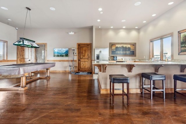 154 W Swift Creek Way, Kalispell, MT 59901 - kitchen with stainless steel fridge, recessed lighting, light stone counters, a breakfast bar area, and dark wood-style flooring