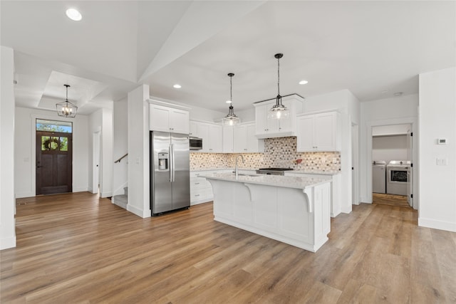 154 W Swift Creek Way, Kalispell, MT 59901 - kitchen featuring appliances with stainless steel finishes, washer and clothes dryer, tasteful backsplash, light wood-type flooring, and white cabinets