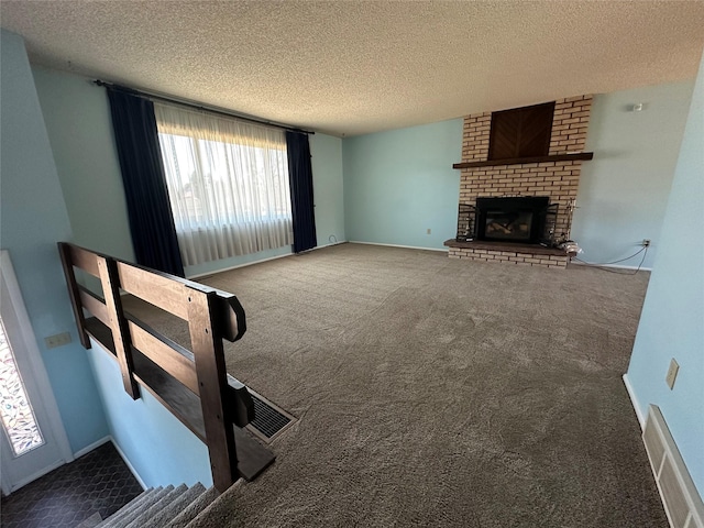 unfurnished living room featuring carpet, visible vents, a fireplace, and a textured ceiling