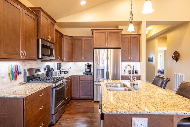 kitchen with visible vents, a sink, vaulted ceiling, stainless steel appliances, and backsplash