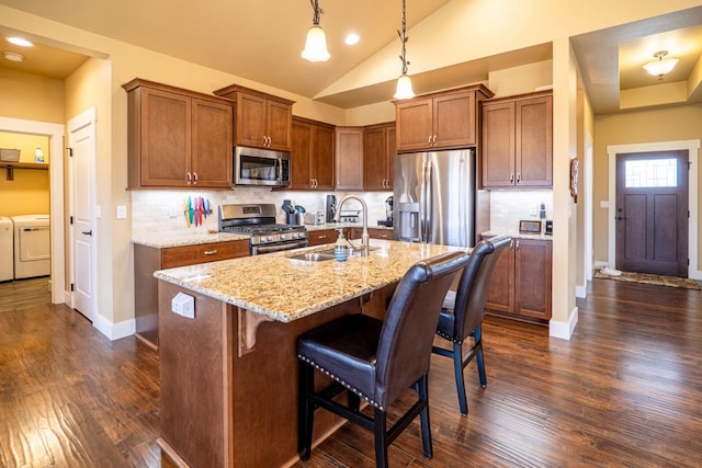 kitchen featuring appliances with stainless steel finishes, brown cabinetry, independent washer and dryer, and a sink