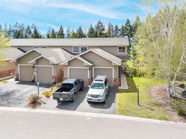 view of front of property featuring driveway, roof with shingles, a front yard, and a garage