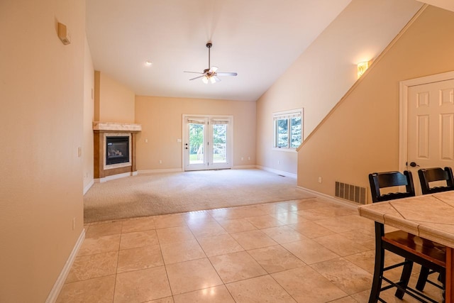 159 Fairway Blvd, Kalispell, MT 59901 - unfurnished living room with light colored carpet, ceiling fan, a tile fireplace, light tile patterned floors, and high vaulted ceiling