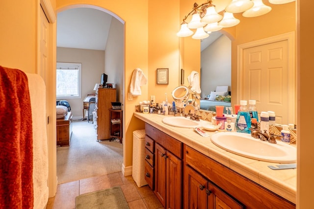 bathroom featuring double vanity, ensuite bath, a sink, and tile patterned floors