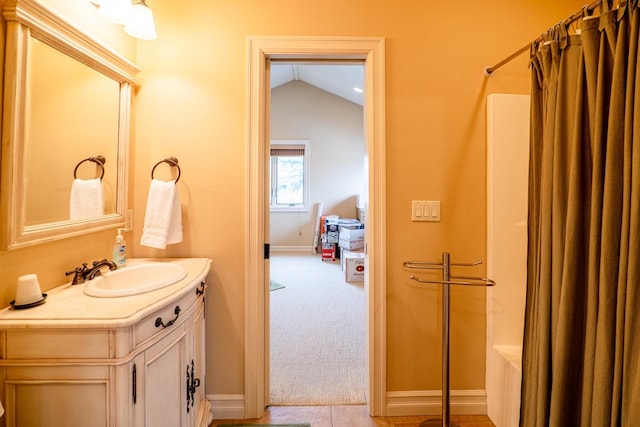 full bath featuring curtained shower, vaulted ceiling, vanity, and baseboards