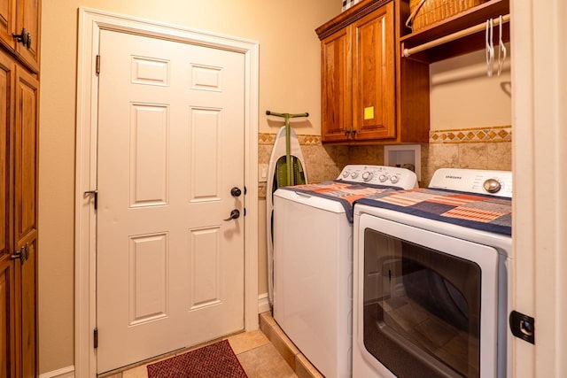 laundry area with cabinet space, a wainscoted wall, separate washer and dryer, tile walls, and light tile patterned flooring