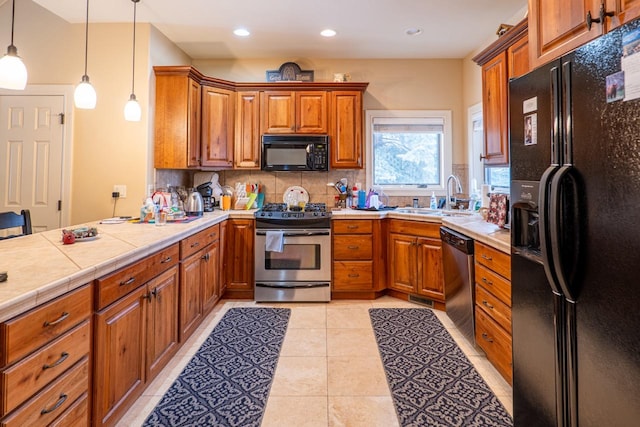 kitchen featuring decorative backsplash, brown cabinetry, a peninsula, black appliances, and a sink