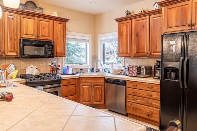 kitchen featuring black appliances, a sink, brown cabinets, and tasteful backsplash