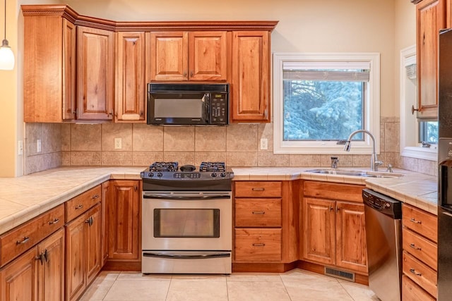 159 Fairway Blvd, Kalispell, MT 59901 - kitchen with appliances with stainless steel finishes, tile counters, brown cabinets, backsplash, and plenty of natural light
