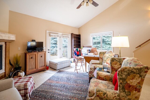 living room featuring a ceiling fan, a glass covered fireplace, a wealth of natural light, and light colored carpet