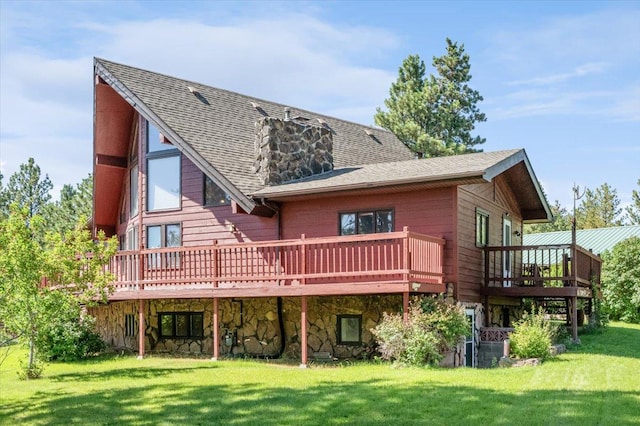 back of property with a deck, a yard, roof with shingles, and stone siding