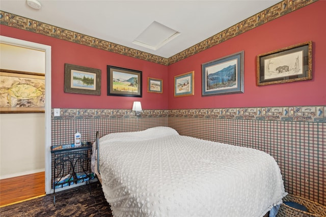 bedroom featuring attic access and wainscoting