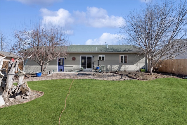 rear view of house featuring entry steps, a patio area, fence, and a lawn