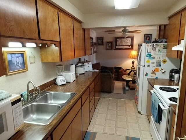 kitchen with a sink, white appliances, brown cabinetry, and light floors