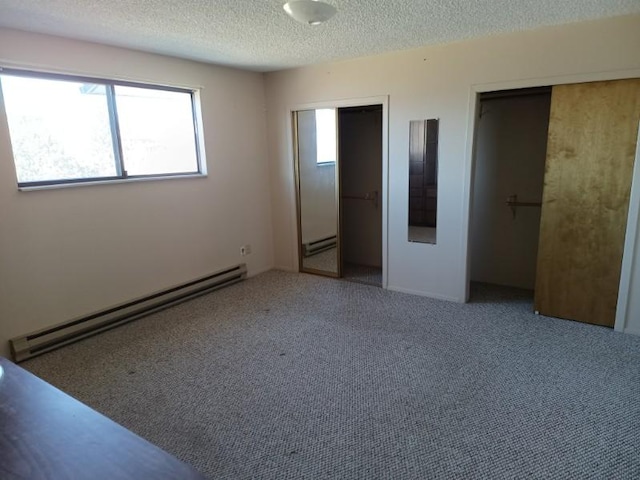 unfurnished bedroom featuring multiple closets, a baseboard radiator, multiple windows, and a textured ceiling