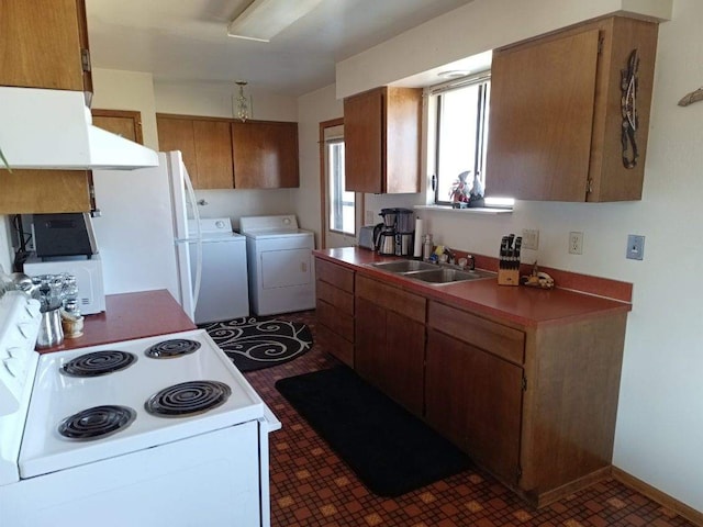 kitchen with white appliances, a sink, baseboards, brown cabinets, and washer and clothes dryer