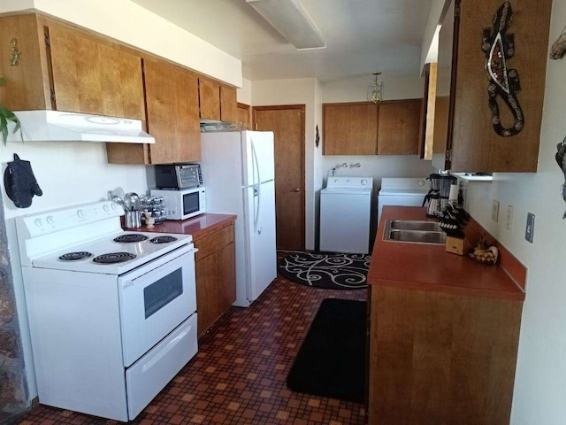 kitchen featuring brown cabinetry, white appliances, independent washer and dryer, and under cabinet range hood