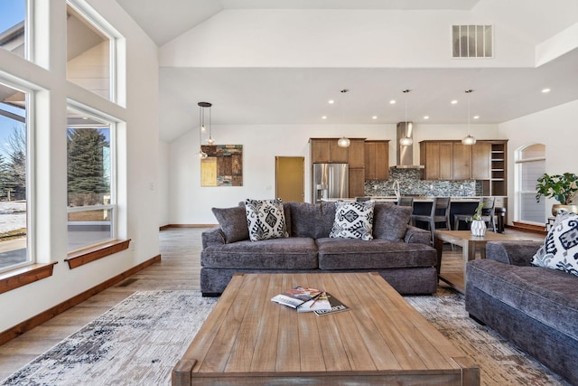 living room with arched walkways, recessed lighting, visible vents, baseboards, and light wood-style floors