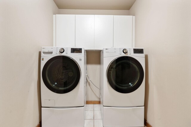 washroom with light tile patterned flooring, independent washer and dryer, and cabinet space