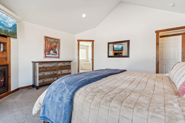 carpeted bedroom featuring vaulted ceiling, a lit fireplace, baseboards, and ensuite bathroom