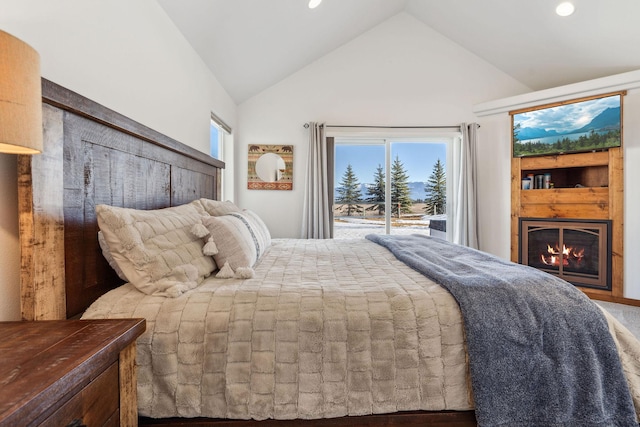 bedroom with access to outside, multiple windows, a lit fireplace, and recessed lighting