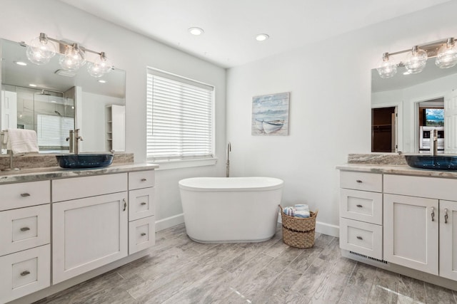 bathroom featuring a wealth of natural light, a shower stall, a sink, and wood finished floors