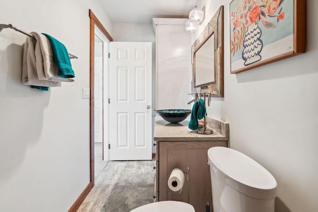 bathroom featuring baseboards, vanity, toilet, and wood finished floors