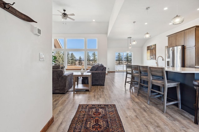 living area with a healthy amount of sunlight, light wood finished floors, baseboards, and a ceiling fan