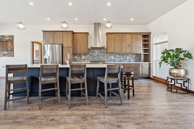 kitchen featuring open shelves, a spacious island, tasteful backsplash, stainless steel fridge, and wall chimney exhaust hood