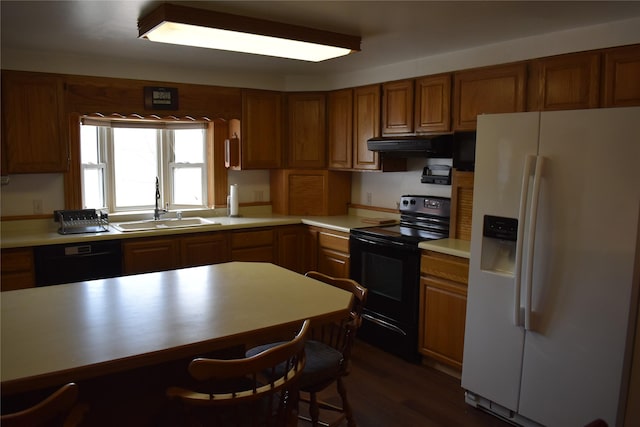 kitchen featuring brown cabinetry, a sink, under cabinet range hood, and black appliances