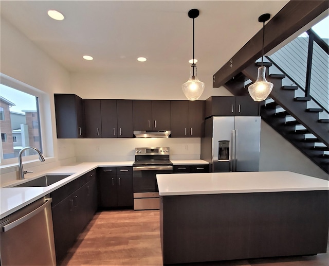 kitchen featuring under cabinet range hood, stainless steel appliances, a sink, and light countertops