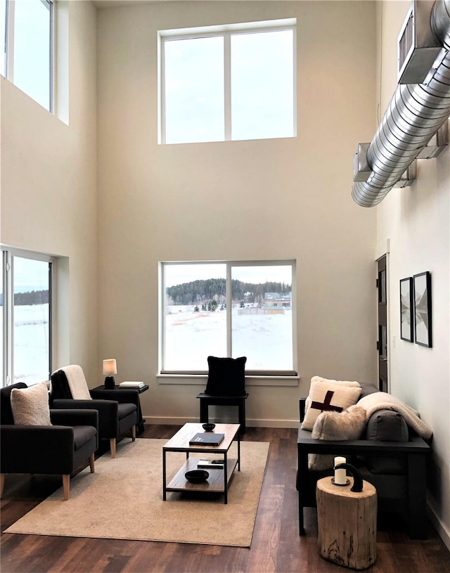 living room with a towering ceiling, baseboards, and wood finished floors