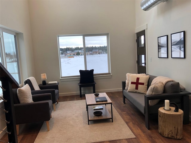 living room with a high ceiling, baseboards, and dark wood finished floors