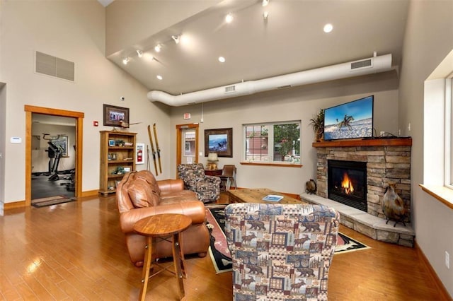 living area with visible vents, a stone fireplace, and wood finished floors