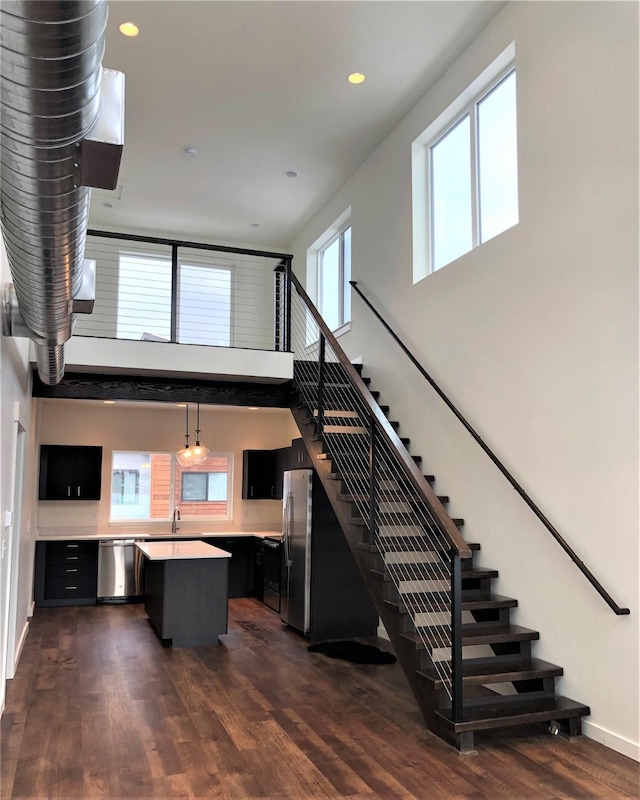 interior space with baseboards, wood finished floors, a towering ceiling, and recessed lighting