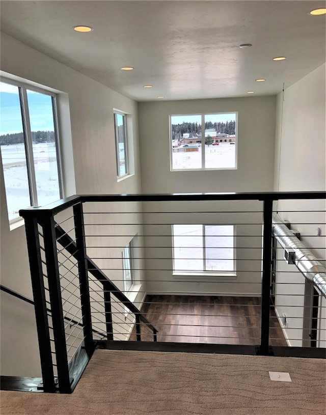 stairway with plenty of natural light, wood finished floors, and recessed lighting