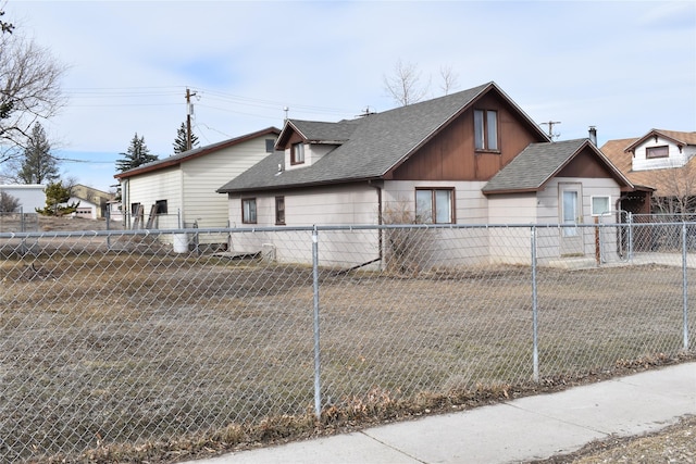 view of side of home with roof with shingles and fence