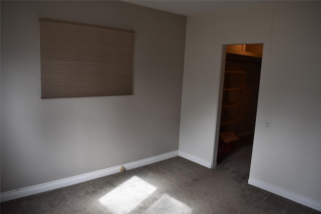 unfurnished room featuring baseboards and dark carpet