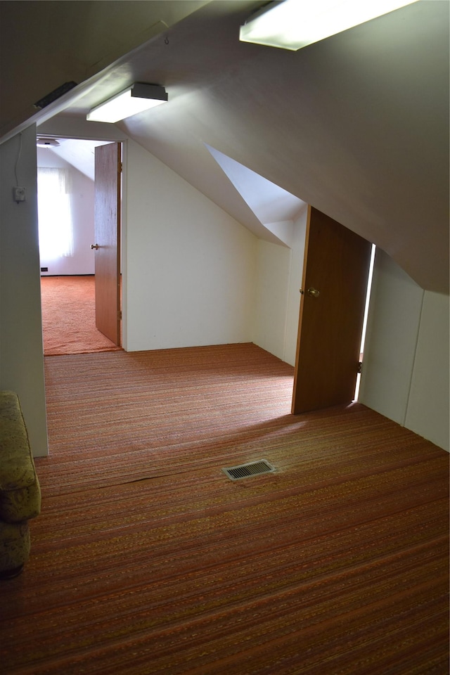 bonus room featuring lofted ceiling, carpet, and visible vents