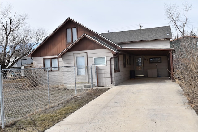 view of front facade featuring a shingled roof, an attached carport, concrete driveway, and fence