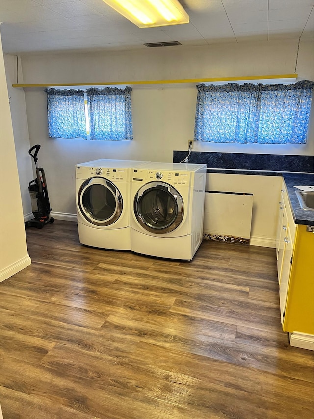 washroom featuring dark wood-type flooring, baseboards, visible vents, and washing machine and clothes dryer